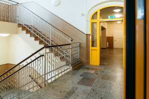 Schulflur mit Treppenhaus und gelbem Eingang