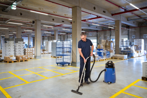 Mitarbeiter des RWS Gebäudeservice reinigt mit einem Industriesauger die Böden in einem Logistiklager.