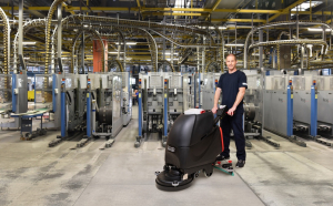 Mitarbeiter des RWS Gebäudeservice reinigt mit einer Maschine die Böden einer Produktionshalle.