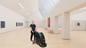 Mitarbeiter von RWS Gebäudeservice reinigt mit einer Bodenmaschine die Ausstellungsfläche einer modernen Kunstgalerie.