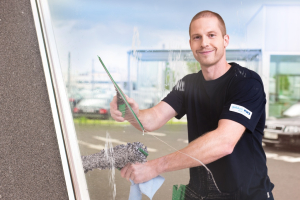 Mitarbeiter von RWS Gebäudeservice reinigt mit professionellem Werkzeug die Fenster eines Bürogebäudes.