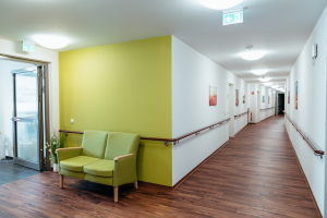 Pflegeheim-Flur mit Sitzgruppe, Handläufen und gepflegtem Holzfußboden