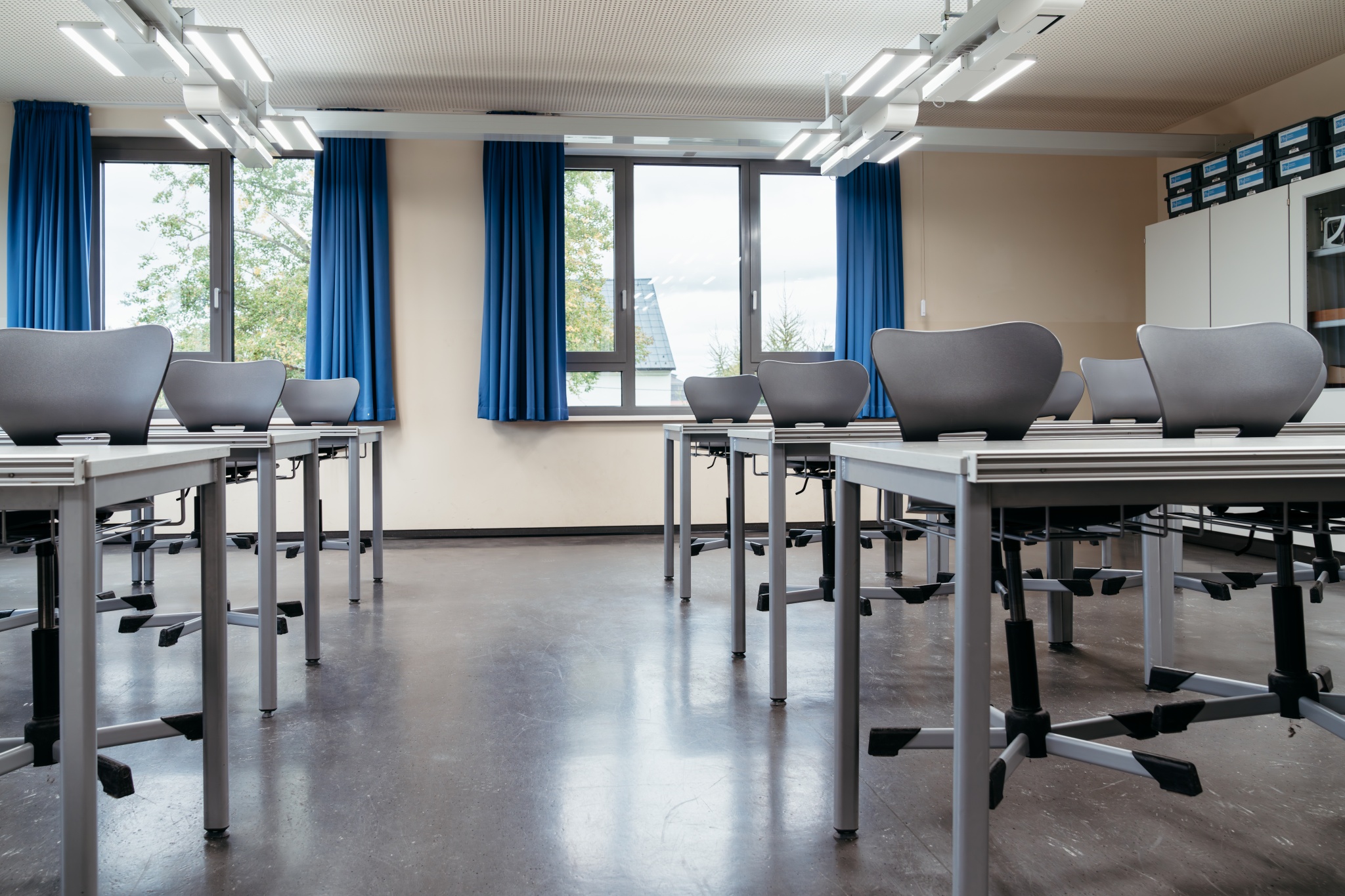 Modernes Klassenzimmer in einer Schule mit Tischen, Stühlen und großen Fenstern