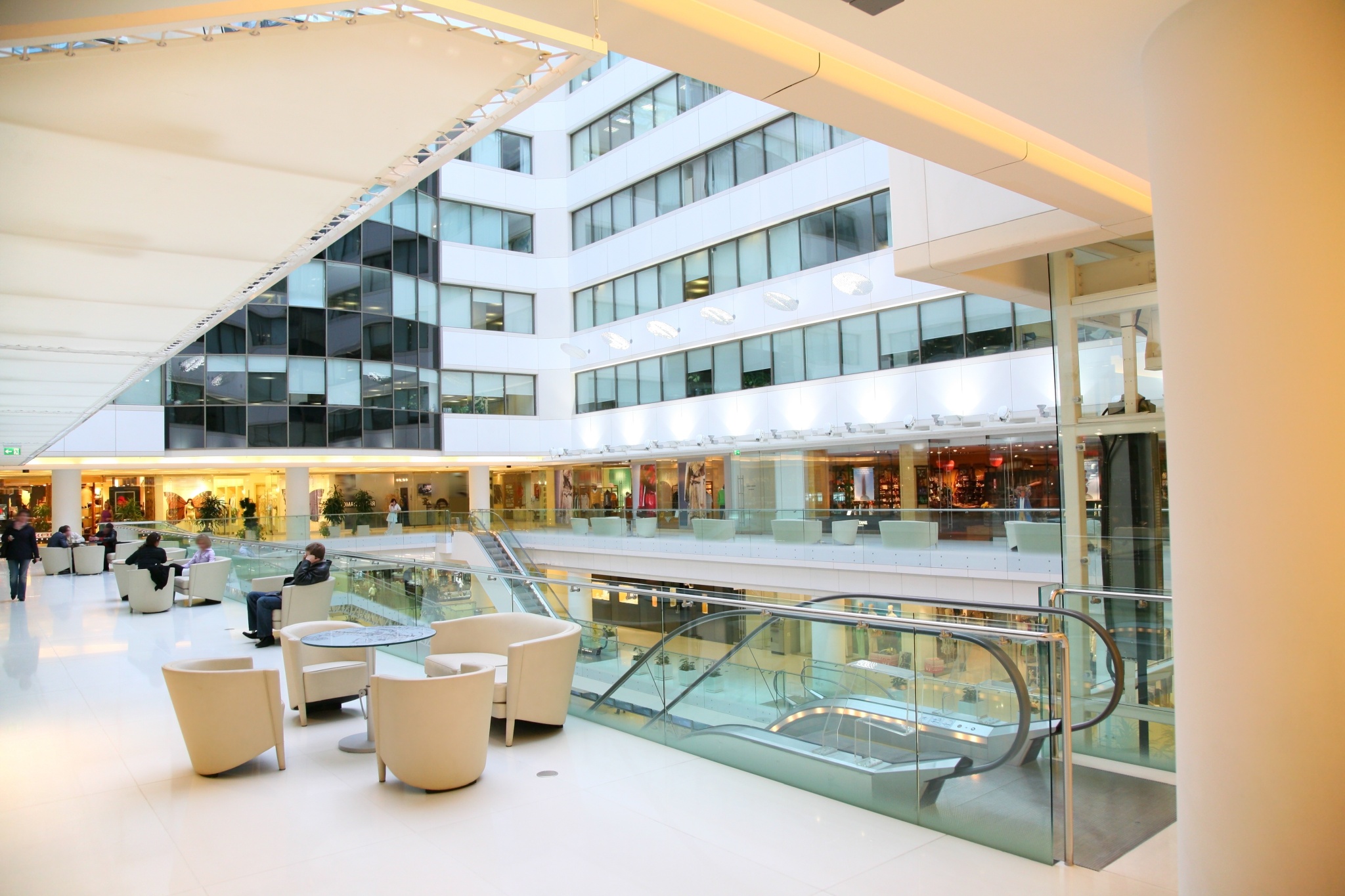 Modernes Einkaufszentrum mit Rolltreppe, Glasfassaden und gepflegtem Lounge-Bereich.