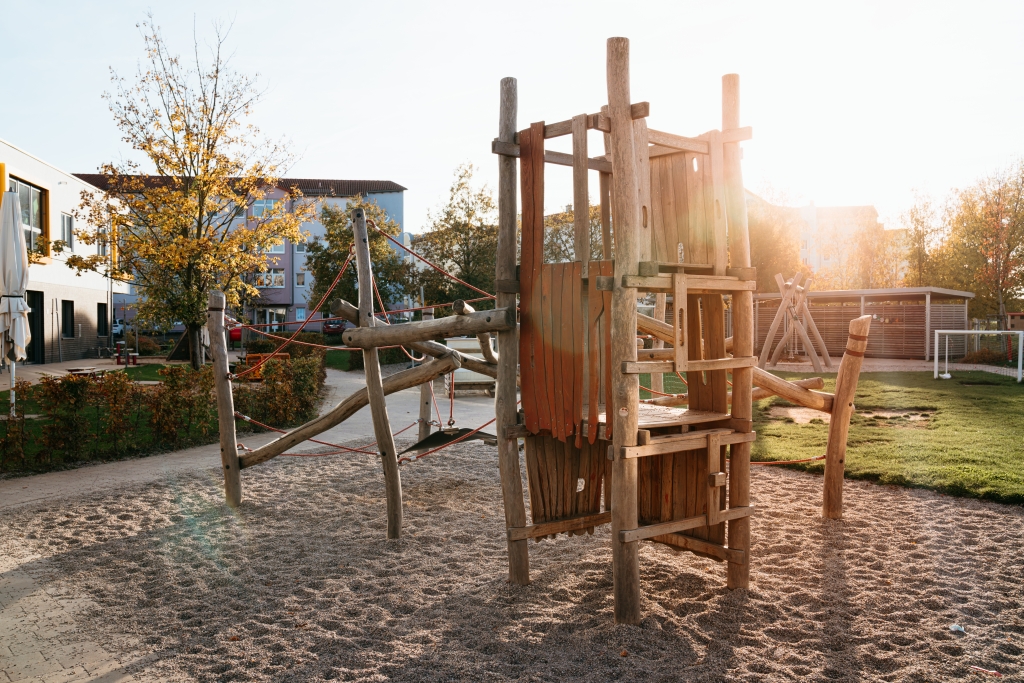 Außenbereich einer Kita mit großem Holz-Klettergerüst im Sand