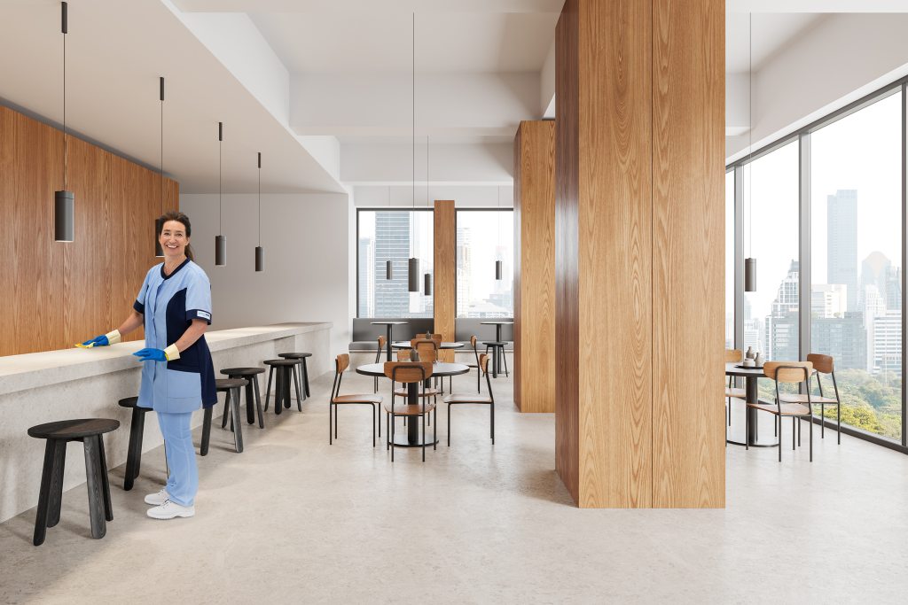 Mitarbeiterin von RWS Gebäudeservice reinigt die Tischoberflächen einer Universitäts-Cafeteria