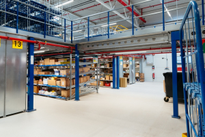 Ordentliches Kleinteillager mit Regalen voller Kartons und sauberem, gepflegtem Boden in einer modernen Industriehalle.
