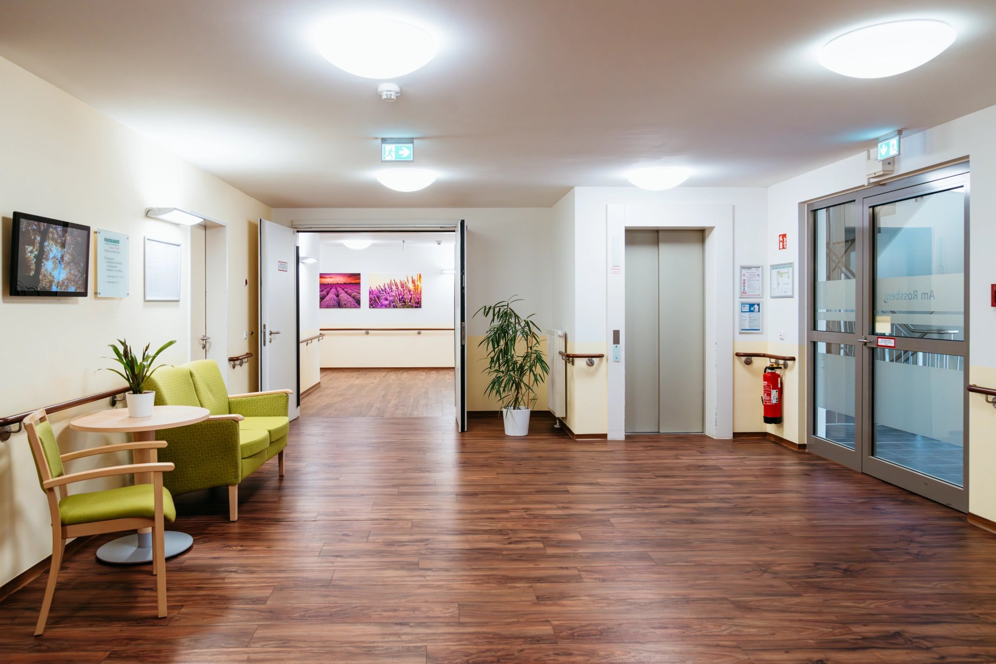 Wohnbereich mit Sitzgruppe, Pflanzen und Aufzug im Pflegeheim