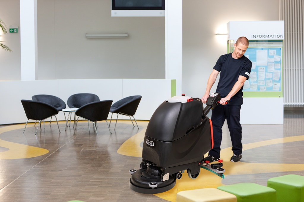 Mitarbeiter von RWS Gebäudeservice reinigt Boden eines Krankenhausfoyers mit professioneller Reinigungsmaschine.