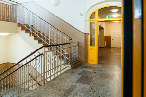 Heller Schulflur mit Treppenhaus und gelber Tür