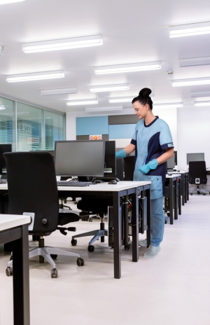 Mitarbeiterin von RWS Gebäudeservice reinigt einen Arbeitsplatz in einem modernen Büro.