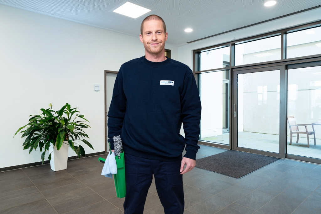 Mitarbeiter von RWS Gebäudeservice reinigt mit professionellem Werkzeug die Glasflächen eines Bürogebäudes.