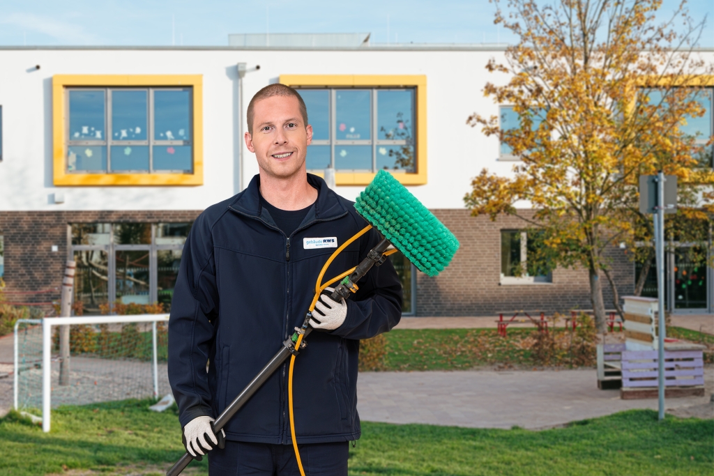Mitarbeiter von RWS Gebäudeservice reinigt mit professionellem Werkzeug die Fenster einer Kita.