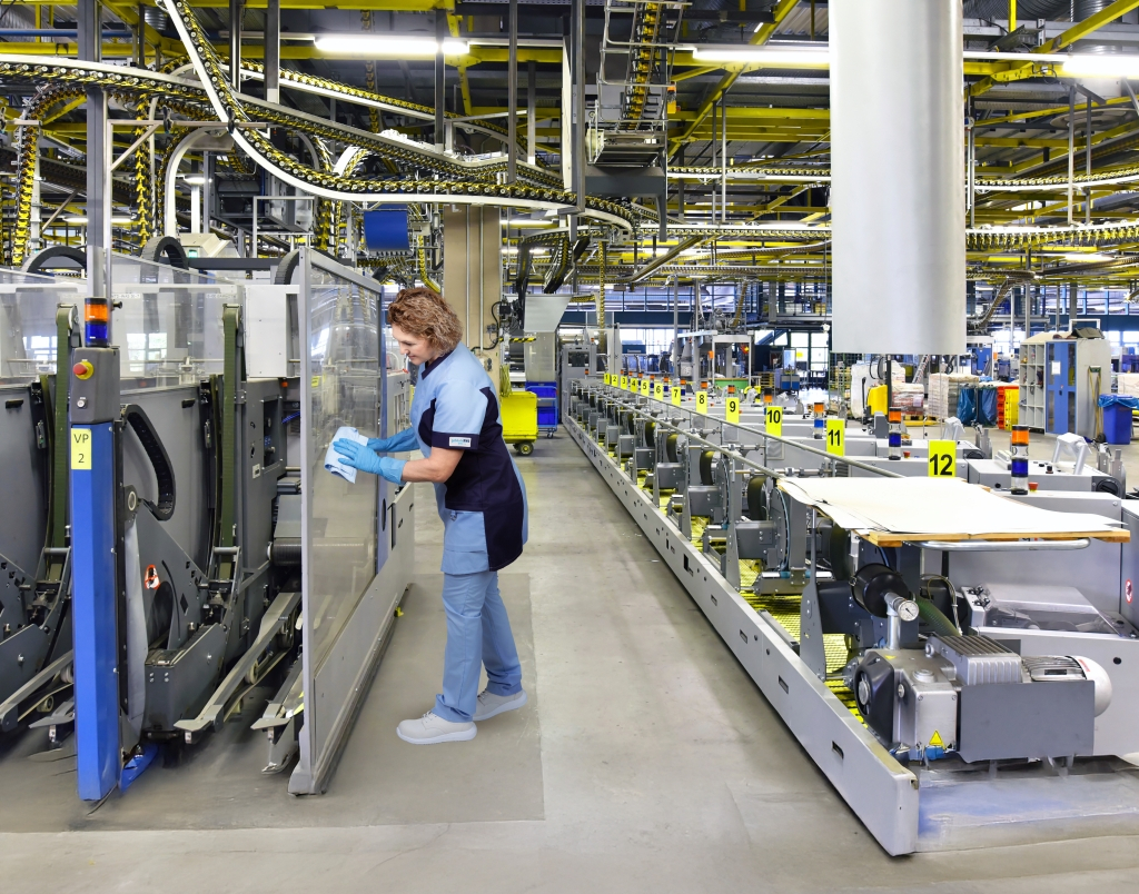 Mitarbeiterin des RWS Gebäudeservice reinigt die Glasabdeckung einer Produktionsanlage.