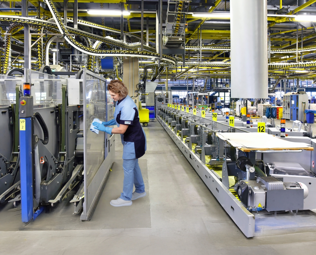 Mitarbeiterin des RWS Gebäudeservice reinigt die Glasabdeckung einer Produktionsanlage.