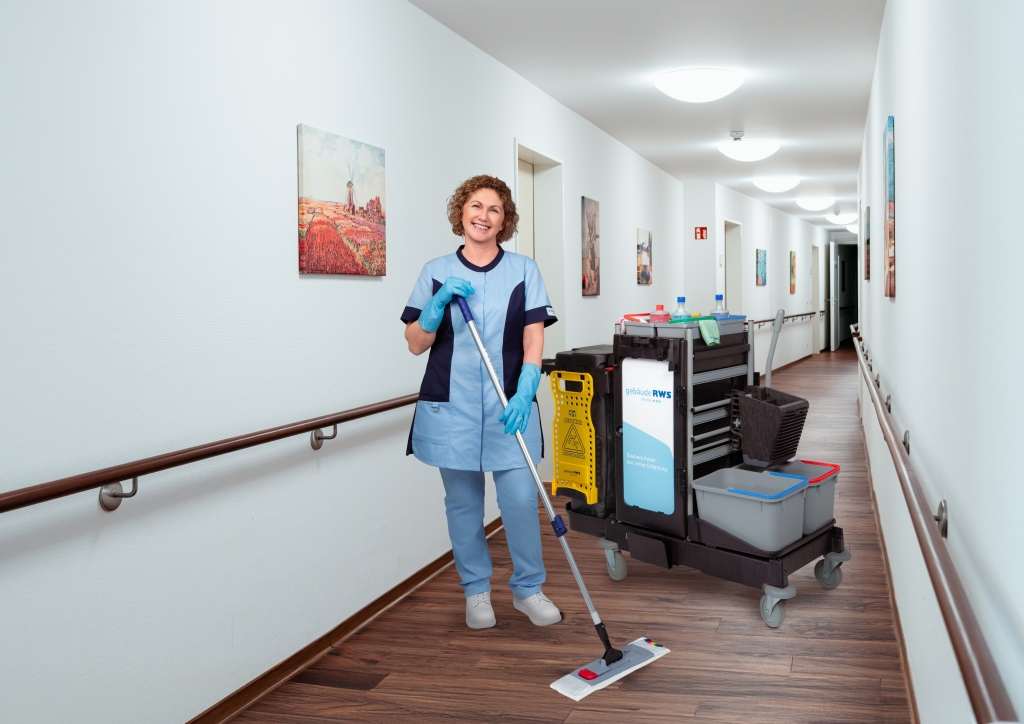 Reinigungskraft mit Reinigungswagen im Flur einer Pflegeeinrichtung