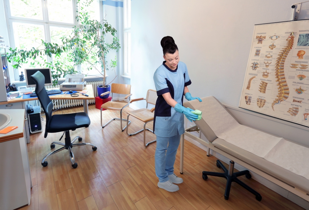 RWS Gebäudeservice Mitarbeiterin reinigt Behandlungsraum einer Arztpraxis für hygienische Sauberkeit.